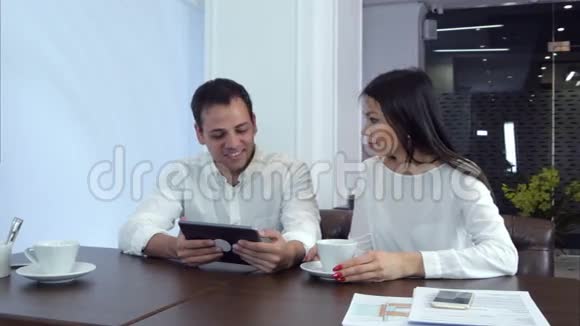 年轻夫妇在平板电脑上嘲笑一些有趣的东西等待他们的午餐视频的预览图