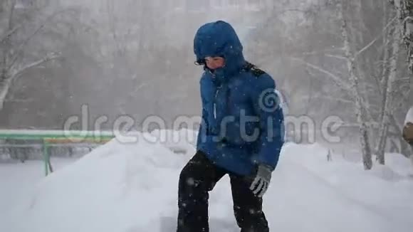 一个孩子跳进冬天公园的雪地里暴风雪视频的预览图