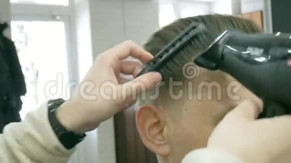 理发店里坐在椅子上时理发师正在给一个带吹风机的男人梳洗视频的预览图
