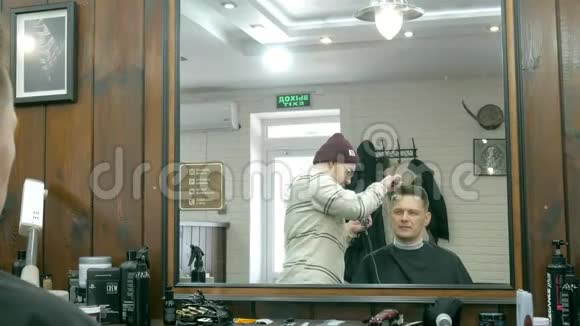 理发店里坐在椅子上时理发师正在给一个带吹风机的男人梳洗视频的预览图