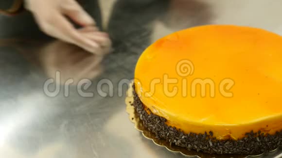 一个糖果师把一个橘子蛋糕放在桌子上视频的预览图