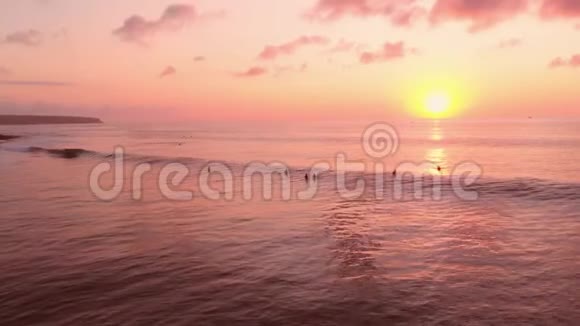在温暖的日落或日出时可在空中观看海洋冲浪者和海浪视频的预览图