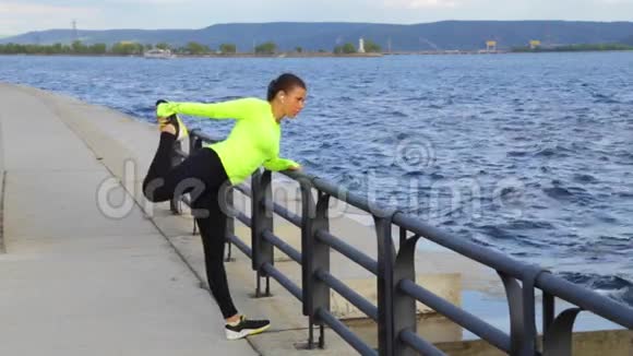 运动妇女锻炼和伸展城市堤山背景视频的预览图
