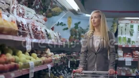 超级市场上有手推车购物的漂亮年轻女子视频的预览图