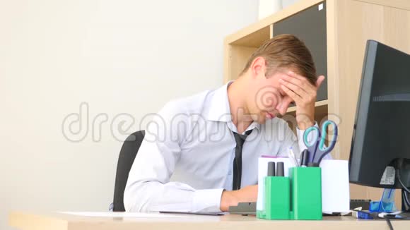 一个在电脑上工作时头部疼痛的男人4k慢动作视频的预览图