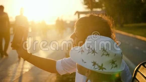 迷人的妈妈和可爱的小女儿在日落时在公园玩和自拍视频的预览图