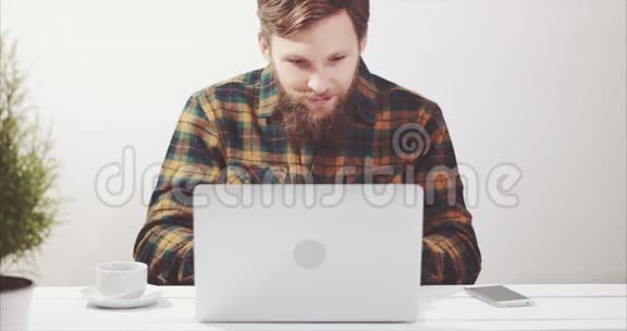 使用笔记本电脑喝咖啡和智能手机聊天的胡子男人视频的预览图