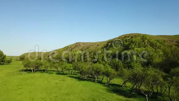 空中镜头飞过风景如画的山谷绿色的田野和山丘岩石悬崖和山脉岩石视频的预览图
