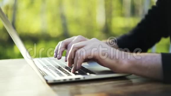 一个人在公园里的笔记本电脑键盘上打字视频的预览图