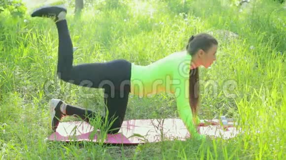 在森林里锻炼身体的女人用哑铃做抬腿动作视频的预览图