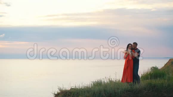 美丽的情侣在悬崖边看日落视频的预览图