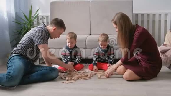 一家人的妈妈爸爸和两个双胞胎兄弟一起在地板上用木块做游戏视频的预览图