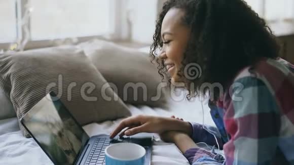 一个性格开朗的混血女孩躺在床上与朋友用手提相机视频聊天视频的预览图