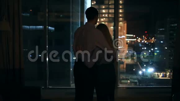 一对男女在夜市的大窗户里张望拥抱视频的预览图
