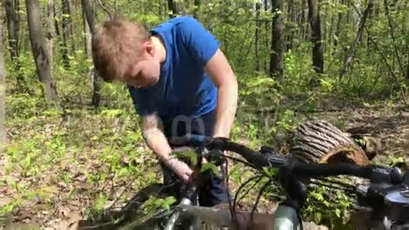 在树林里修自行车的男孩视频的预览图