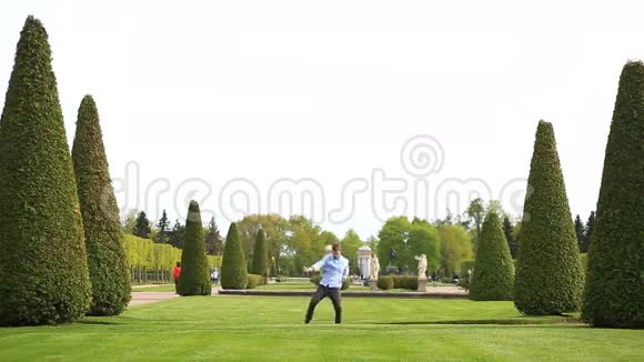 有趣的白种人年轻男子在夏天的晴天公园的绿草草坪上跳舞视频的预览图