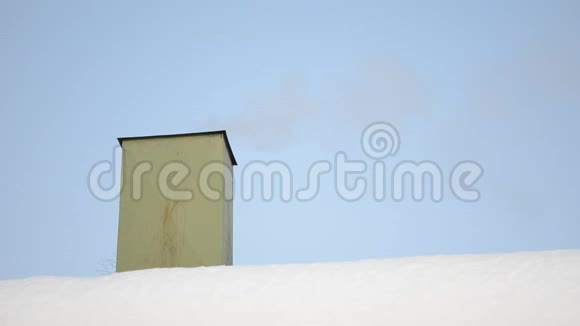 冬天从雪顶的绿色烟囱冒出来的烟视频的预览图