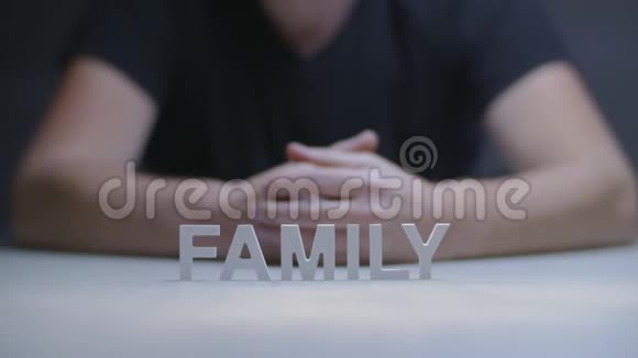 男人的双手在灰色背景下显示由白色字母组成的单词家族视频的预览图