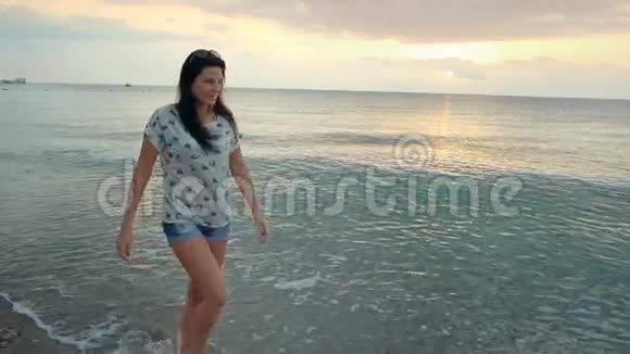 苗条的黑发女孩走在海滩上享受和灵感的日出视频的预览图