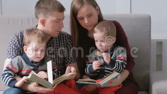 一家人的和两个双胞胎兄弟坐在沙发上看书家庭阅读时间视频的预览图