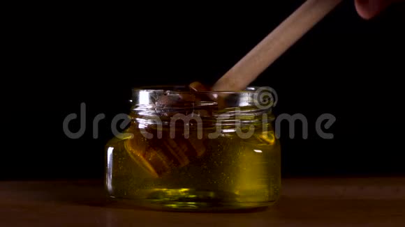 蜂蜜从黑色背景的蜂蜜勺上滴下健康的有机浓蜂蜜从木制的蜜匙中蘸取视频的预览图