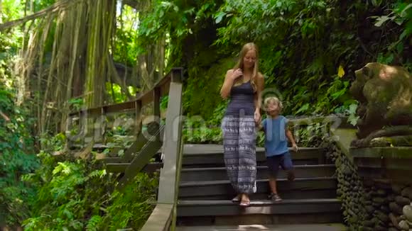 一名年轻女子和她的小儿子在印度尼西亚Ubud参观猴子森林生态公园的慢镜头视频的预览图