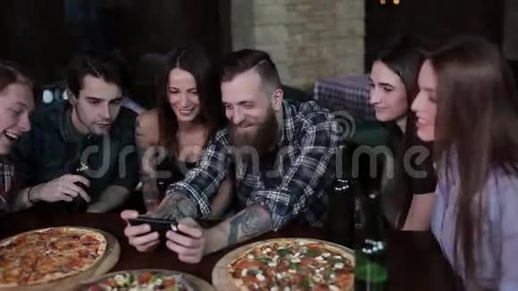 一群快乐的朋友在咖啡馆里看着电话里的照片笑着视频的预览图