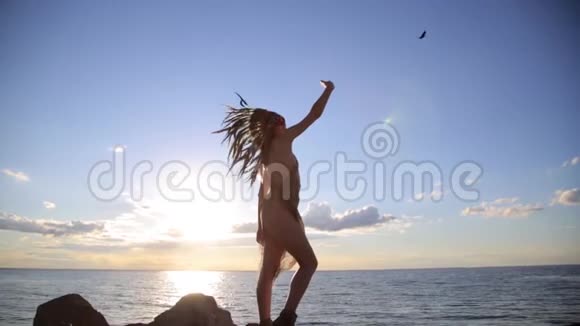 年轻的微笑美国土著妇女穿着波希米亚风格的太阳服日落时在海边自拍视频的预览图
