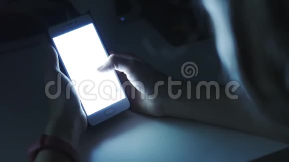 女人在黑暗的房间里用智能手机视频的预览图