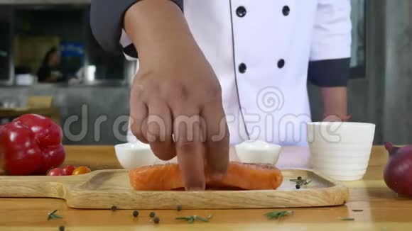 将美味的主厨或烹制新鲜的三文鱼片调味加入海盐和辛辣辣椒视频的预览图