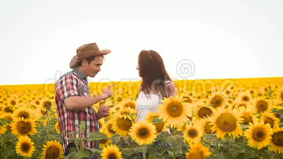 跳舞的男人和一个女孩戴着一顶帽子在田野上戴着黄色的向日葵视频的预览图