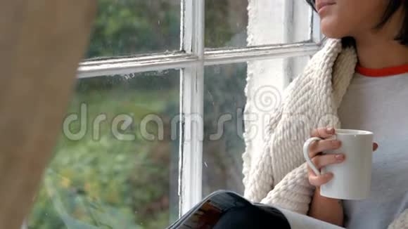 坐在窗台上喝杯咖啡的贵妇人视频的预览图