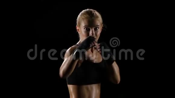 慢动作女拳击手在黑暗的工作室里训练自己视频的预览图