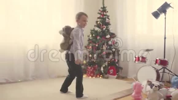 一个男孩在圣诞树旁拿着玩具包视频的预览图