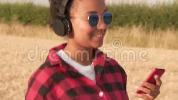 非洲裔美国少女少女在日落或日出时用无线耳机听音乐视频的预览图