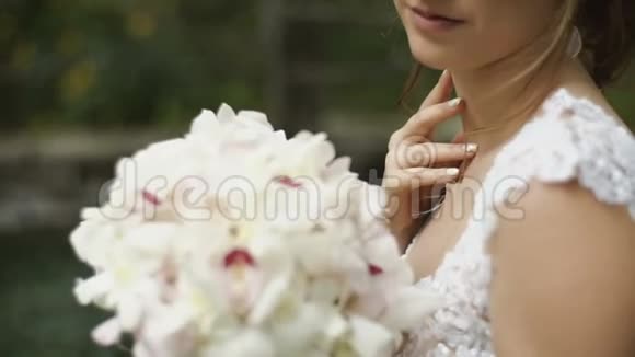 浪漫的幸福新娘站在大自然的背景上捧着花束微笑视频的预览图