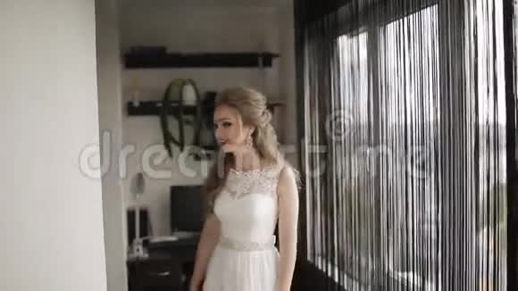 幸福的新娘微笑着在房间里快乐地旋转着新娘在房间里等新郎幸福地微笑着视频的预览图