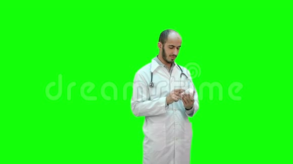 男医生在绿色屏幕上仔细阅读一瓶药丸的药品标签Chroma键视频的预览图