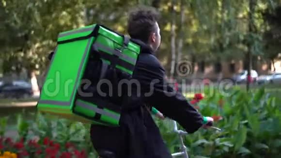 送货员带着绿色背包骑着自行车穿过城市带着食物送货视频的预览图