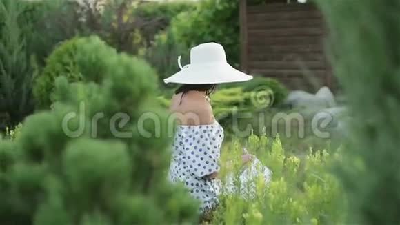 中年妇女戴着太阳帽穿着绿色的树木和草地视频的预览图