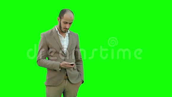 穿西装的忙碌男人在绿色屏幕上的手机上发送短信Chroma键视频的预览图