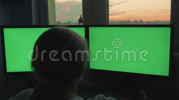 十几岁的女孩坐在两个大显示器前情绪化地交谈绿色屏幕视频的预览图
