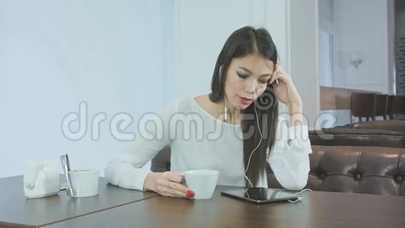 打呵欠的无聊女孩在咖啡馆用平板电脑喝咖啡视频的预览图