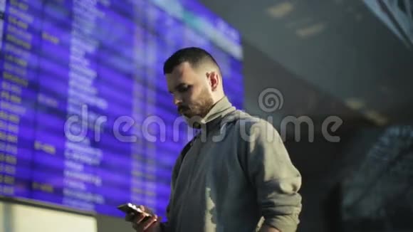 那个年轻人正用手机敲电话号码站在机场的信息板旁边视频的预览图