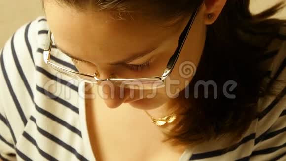 戴眼镜的年轻女孩低头看着关门视频的预览图