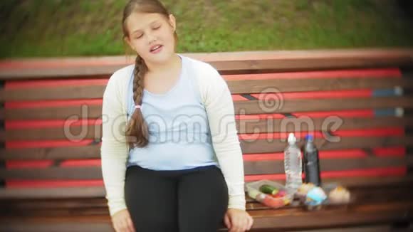 亲近一个可爱的小胖女孩在蛋糕和蔬菜之间潜水坐在咖啡馆的长凳上概念是一个视频的预览图