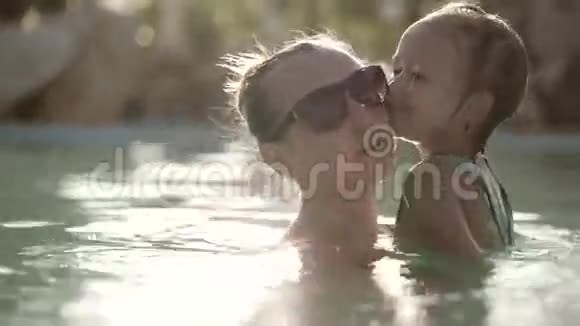 快乐美丽的女人轻轻地抱着她的女儿游泳池视频的预览图
