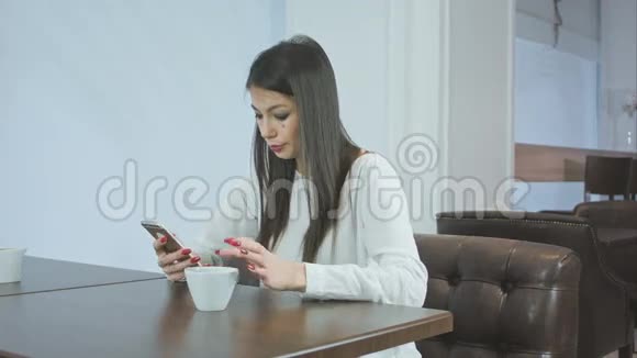 在咖啡馆里用电话四处张望的漂亮女孩视频的预览图