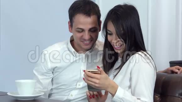 两个同事在咖啡馆里看着手机上的照片笑了起来视频的预览图