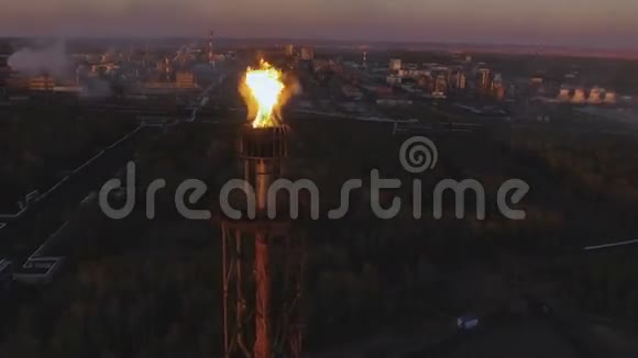 日落时分一座塔在树林间的炼油厂上挂着火炬空中景观视频的预览图
